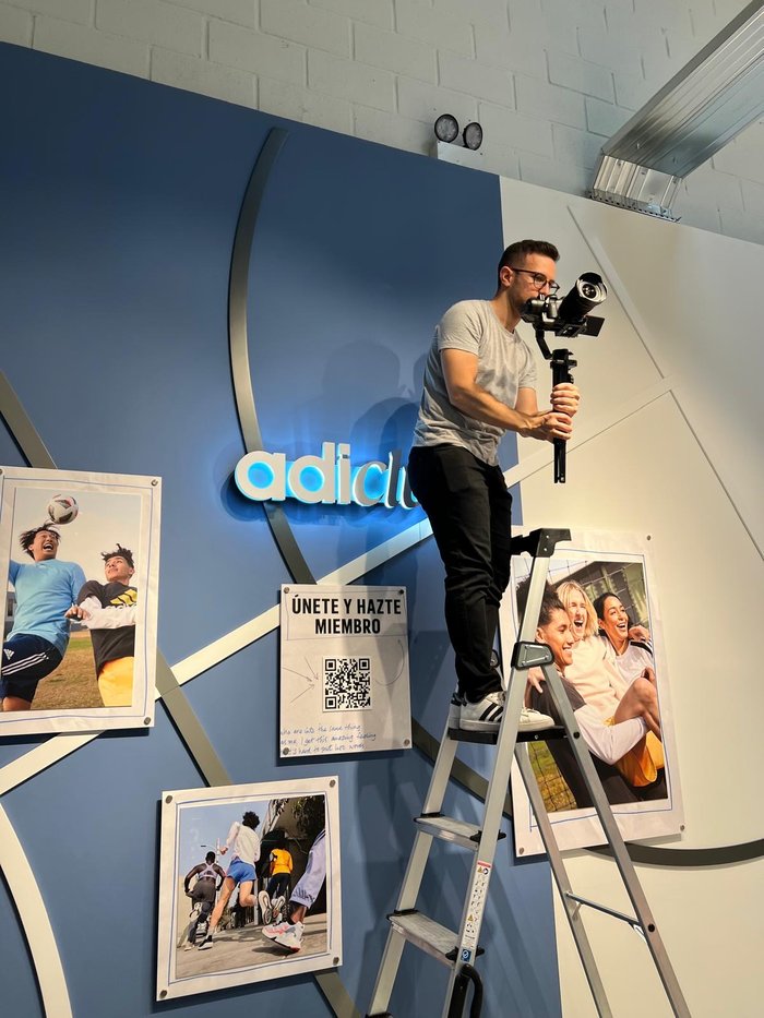 Crew member filming from a ladder at an Adidas storefront display