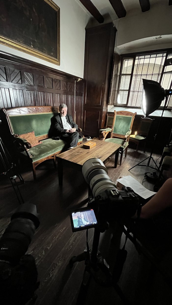 Filming an interview in a period room with dark wood panelling and leaded windows