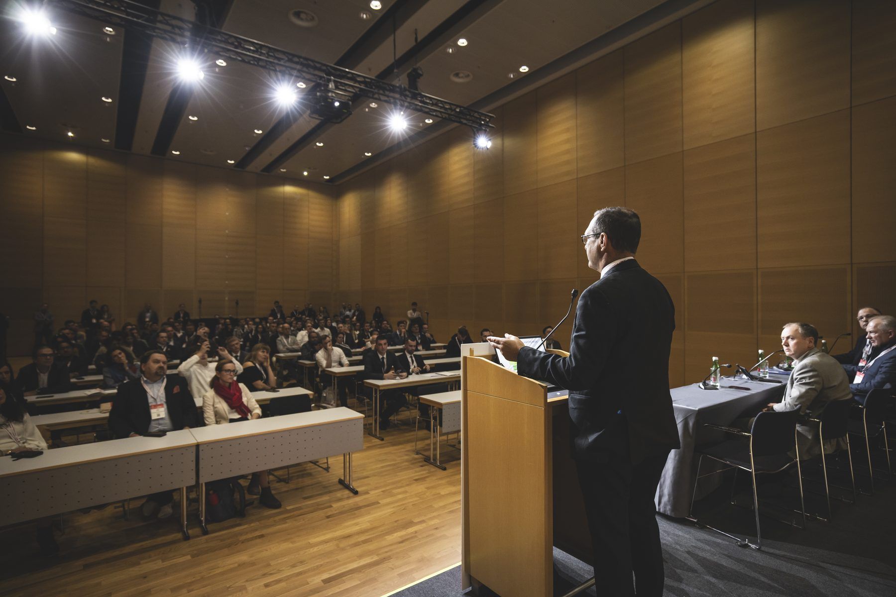 Speaker addressing the seated audience from the podium at a medical congress