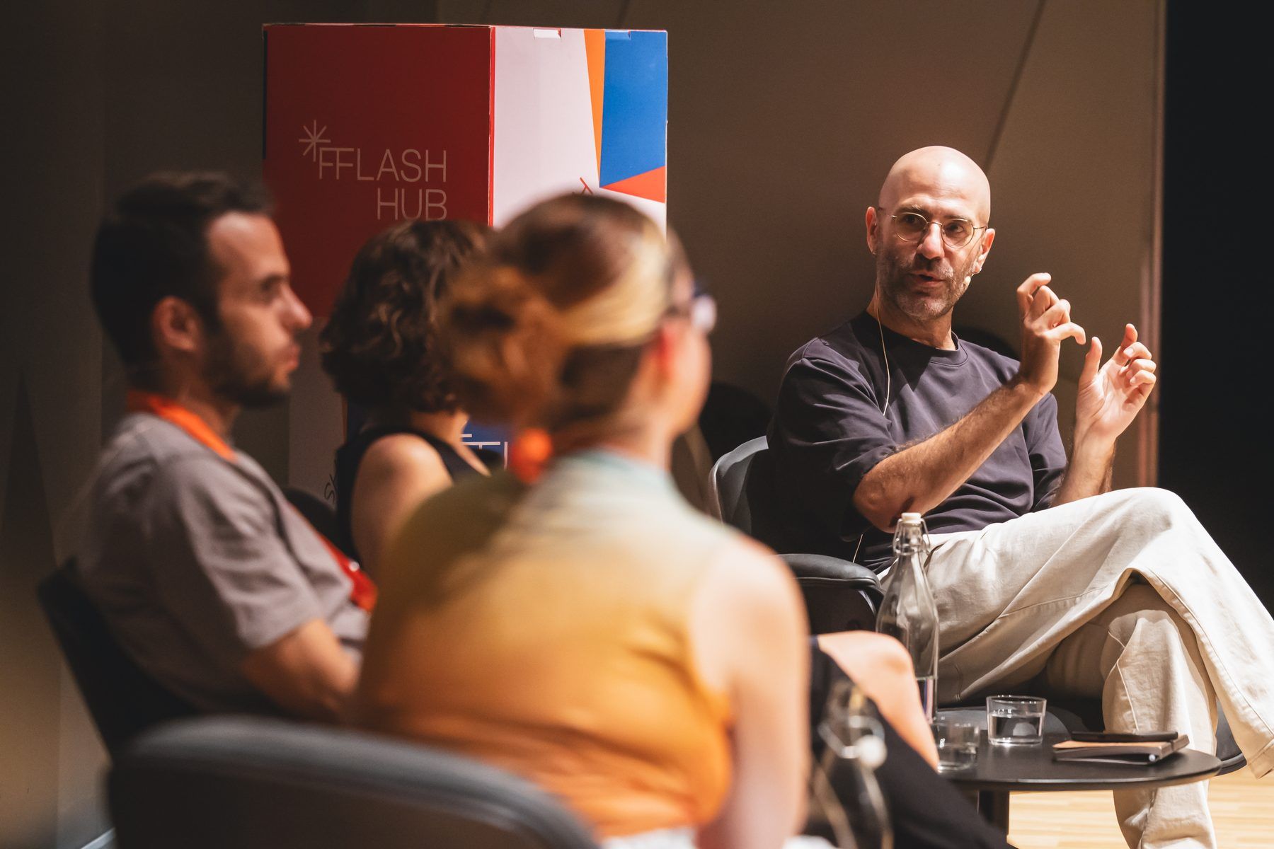 Four people in a panel discussion on stage, the Flash Hub sign behind them